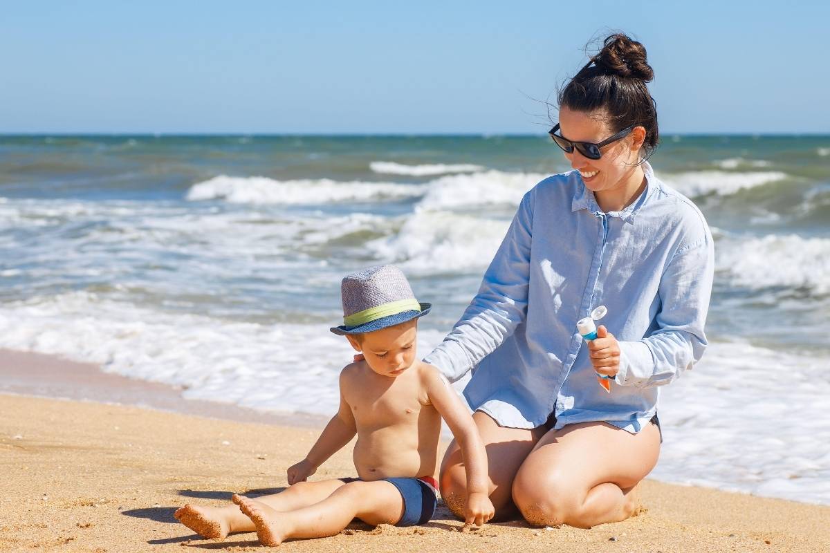 A woman applying sunscreen to her child's skin