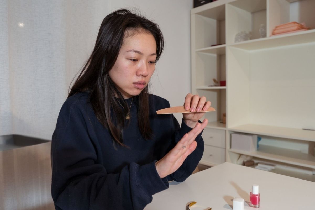 A woman giving herself a nail manicure at home