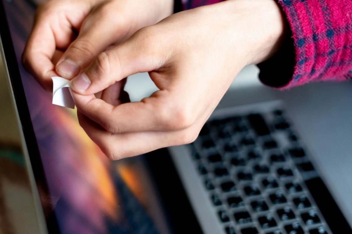 A woman placing a piece of paper over her webcam to use it as a shield